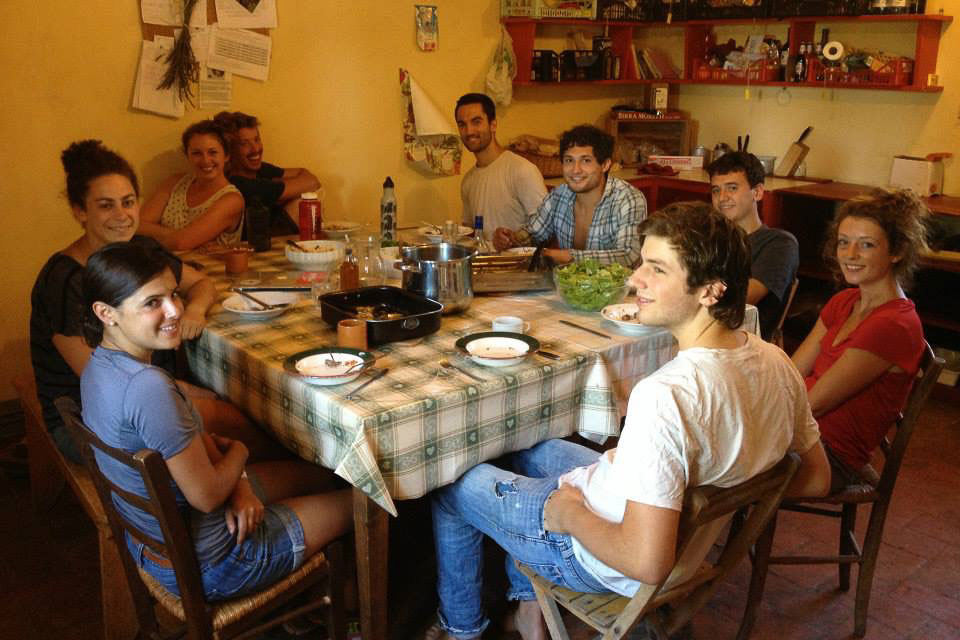 9 interns sitting down to a meal in the Casa Pulcinelli kitchen.