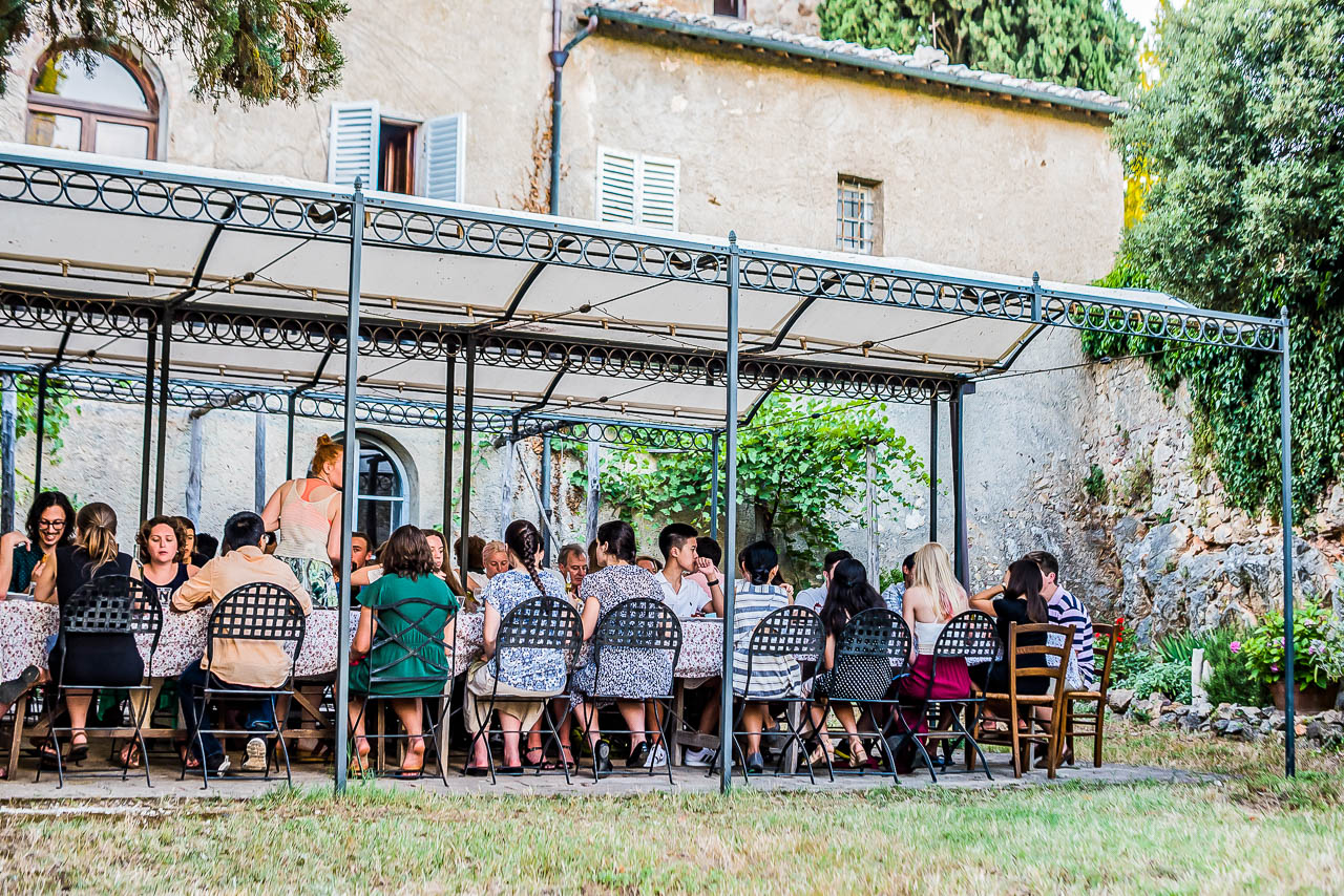 Large group of farming interns sitting down for dinner outside.