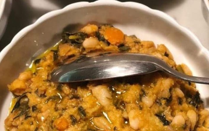 A close-up photo of a bowl of ribollita with a spoon.