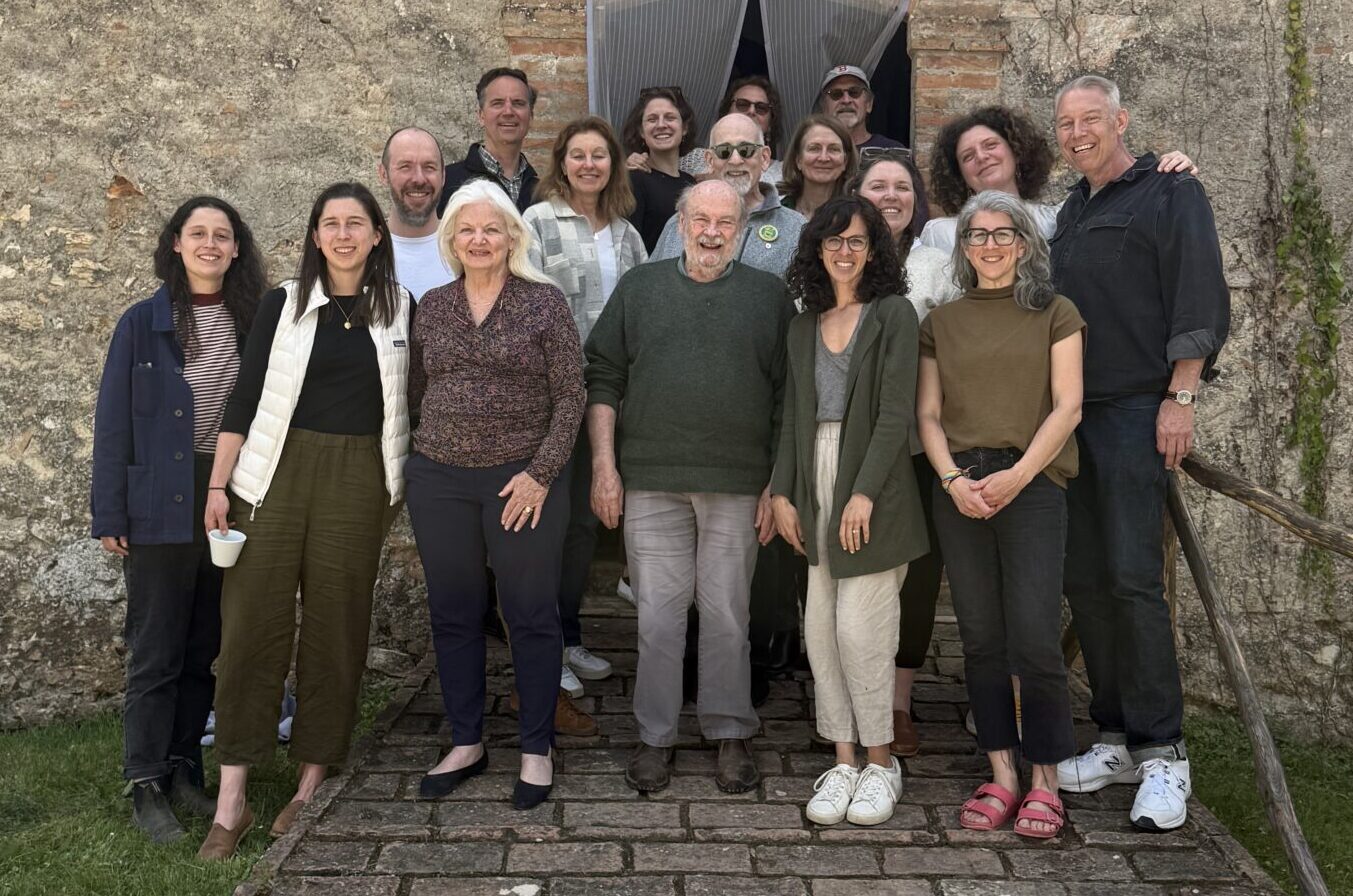 A photo of 17 people on a brick ramp, with a rustic old stone building behind them. The photo is a mix of 12 board members and 5 staff (Italian and US!).