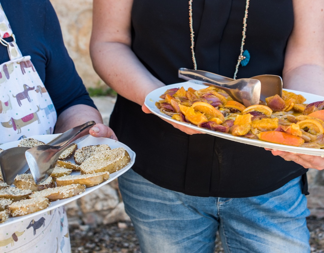 A close-up photo of two people holding platters of food.